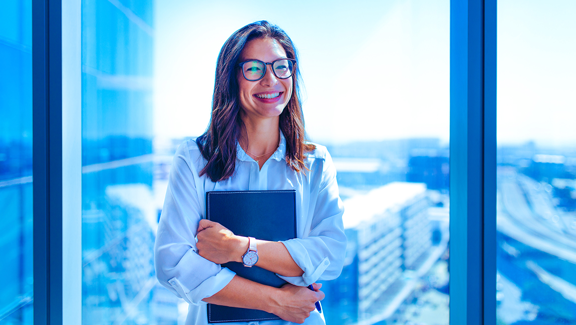Smiling businesswoman standing in front of glass window