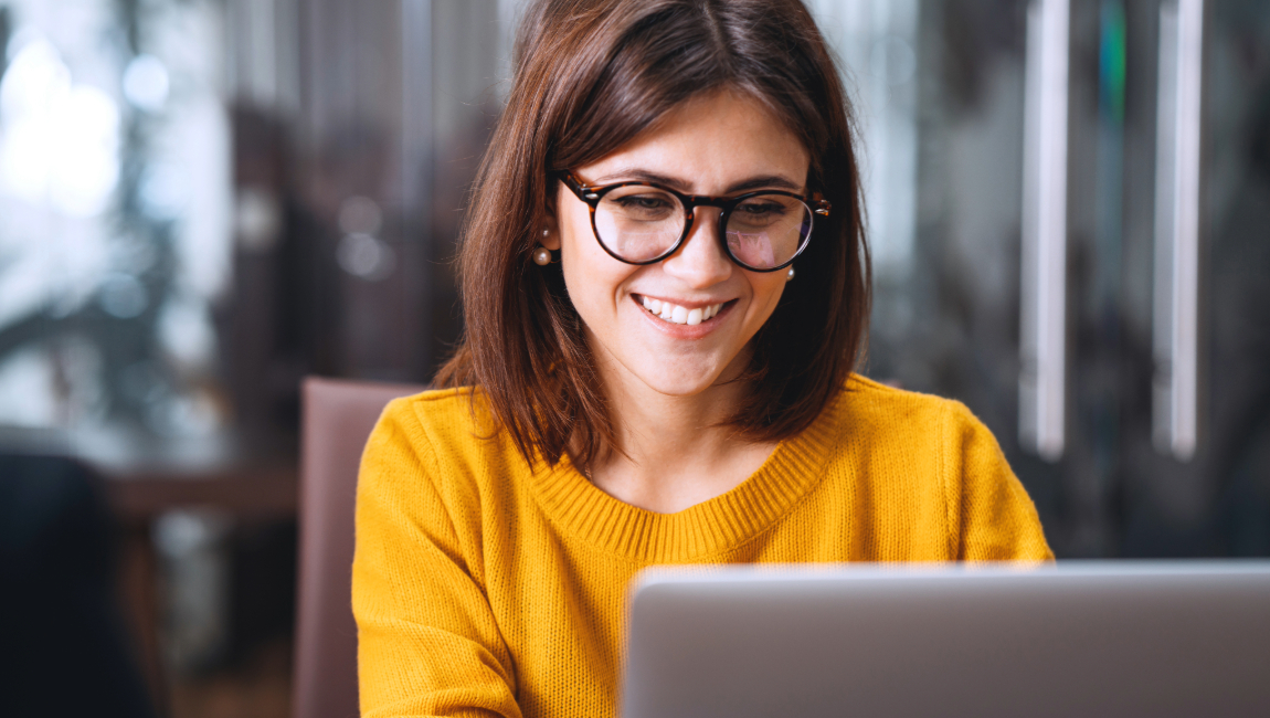 Happy businesswoman wearing glasses sitting with a laptop