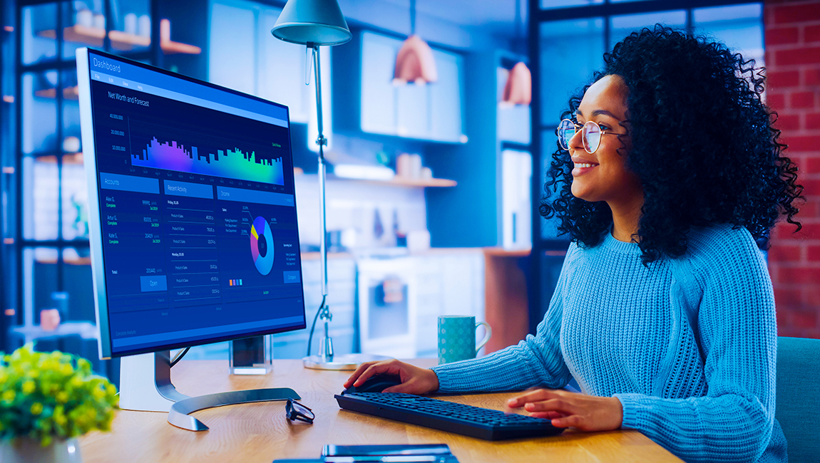 Woman working at desk with charts displayed on her computer monitor