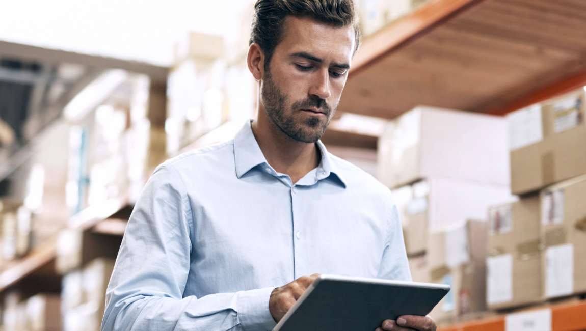 Businessman with tablet walking in warehouse