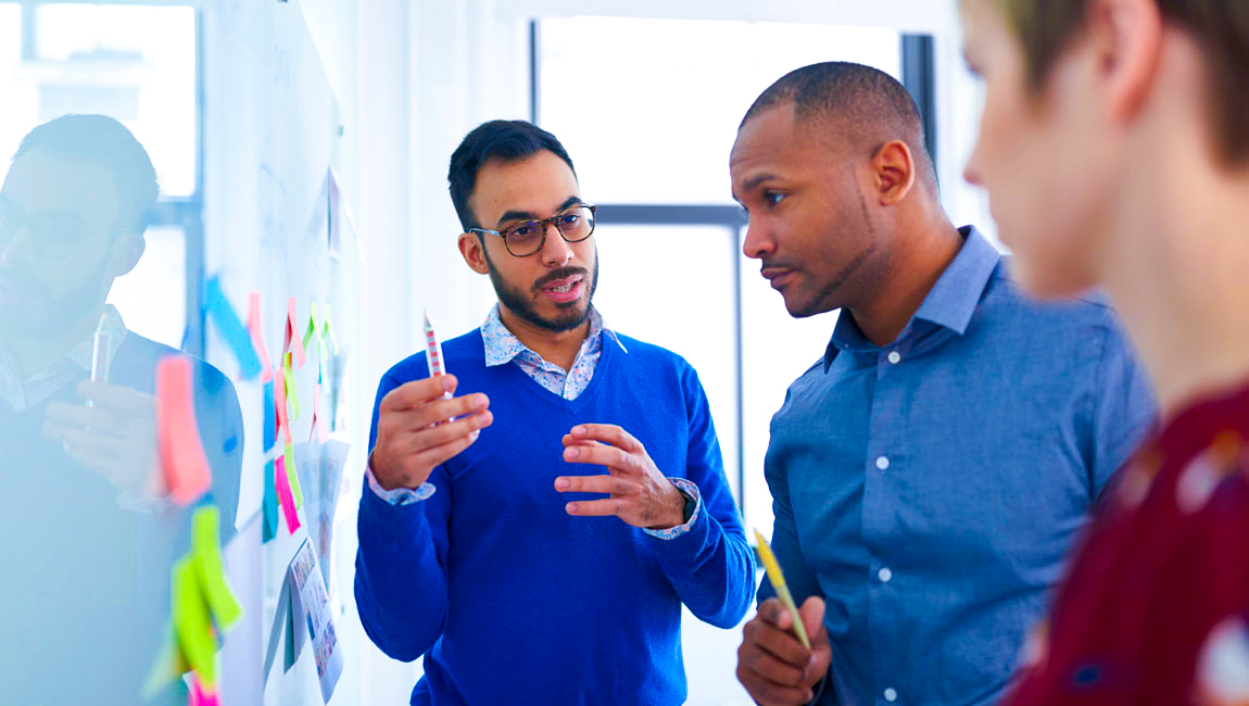 Three colleagues having a discussion at a whiteboard