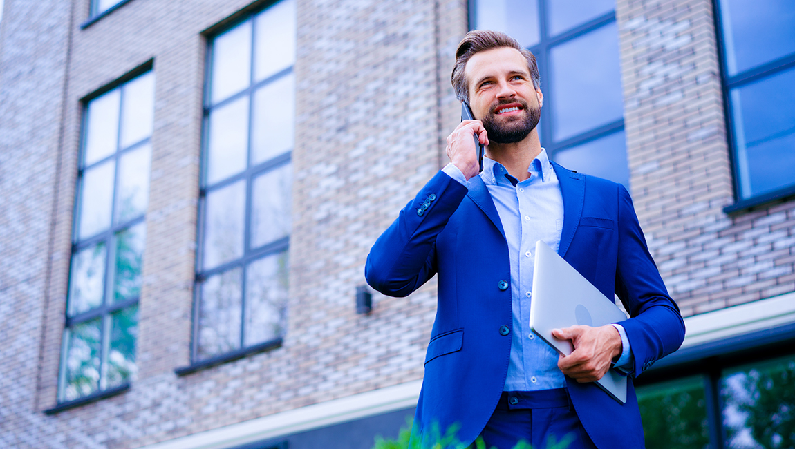 Businessman talking on cell phone while walking outside of office building