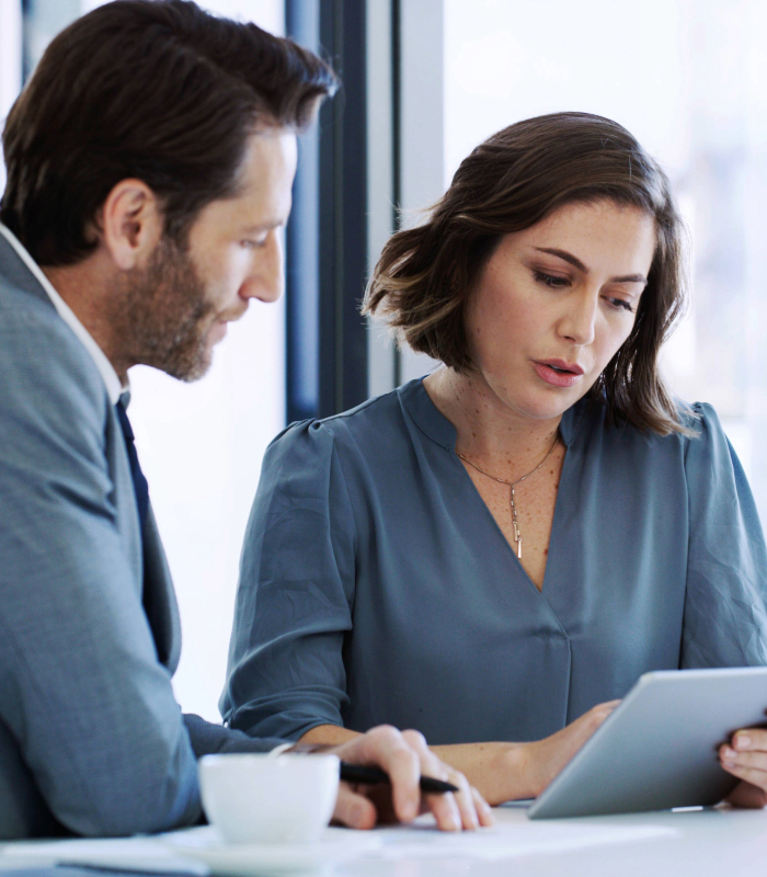 Two businesspeople in an office working on a digital tablet